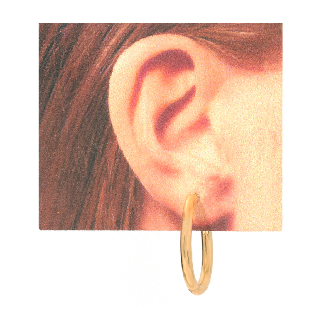 A single gold hoop earring shown on a person&