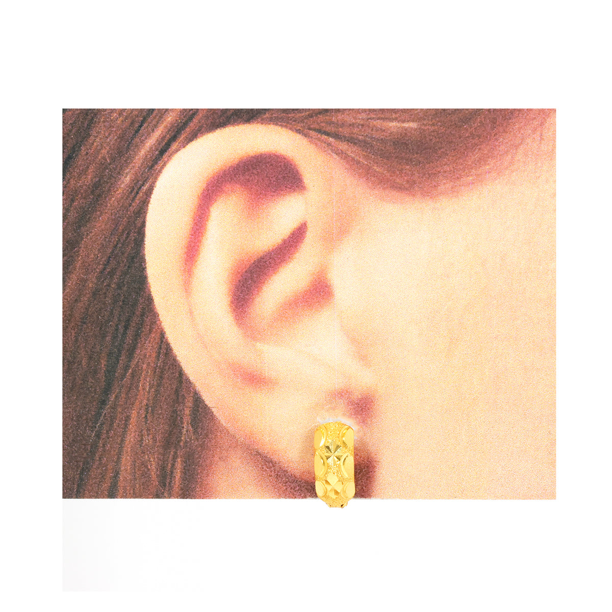 Gold hoop earring worn by a person with brown hair.