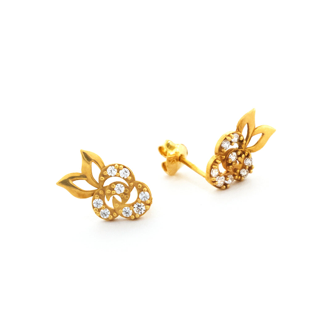 Gold earrings with leaf design and clear stones on a white background