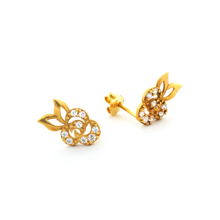 Gold earrings with leaf design and clear stones on a white background