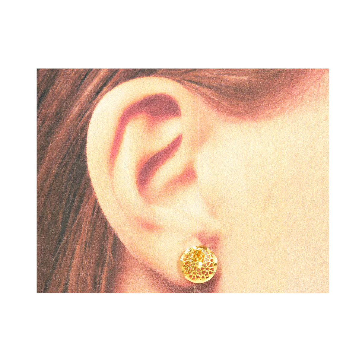 Gold earring worn by a person with brown hair.