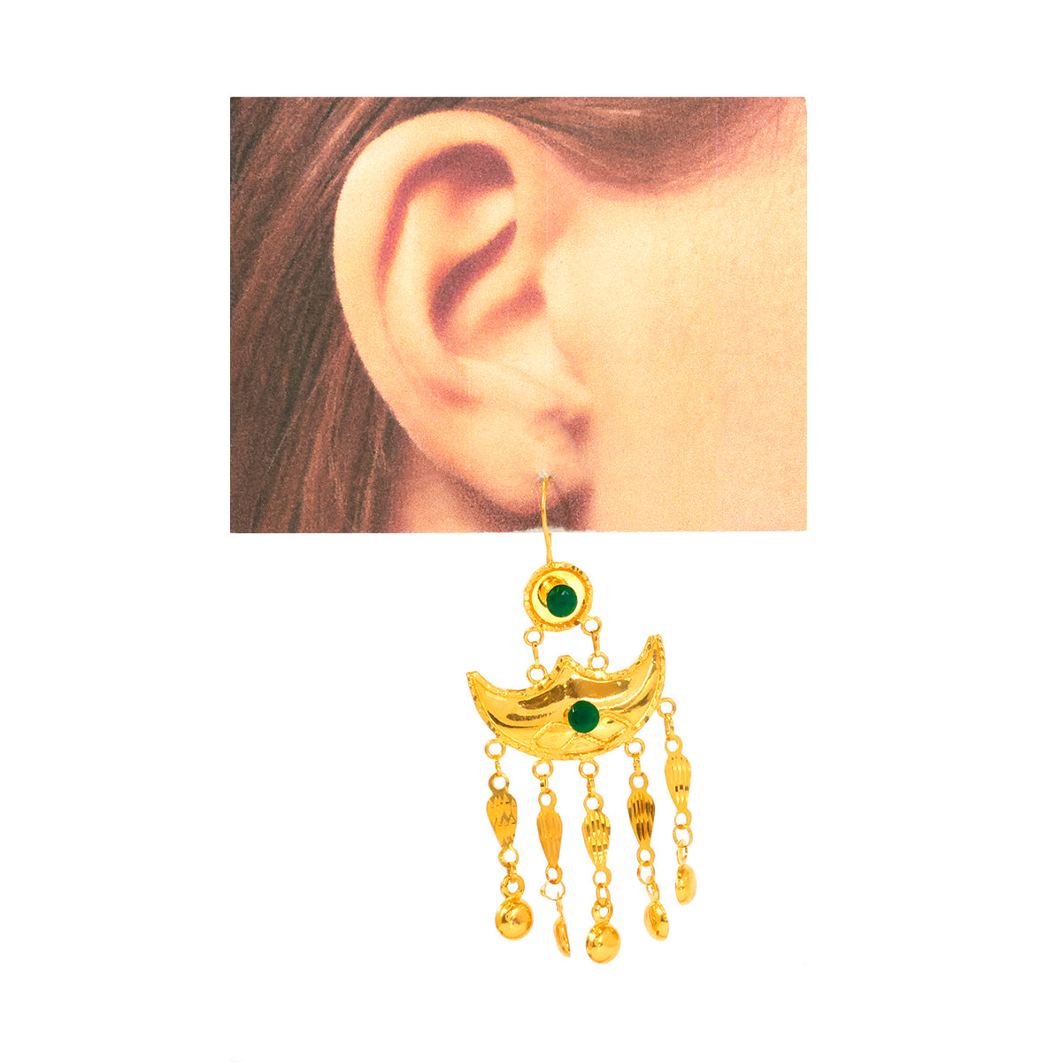 Gold earring with green gemstones worn on an ear, displayed against a white background.