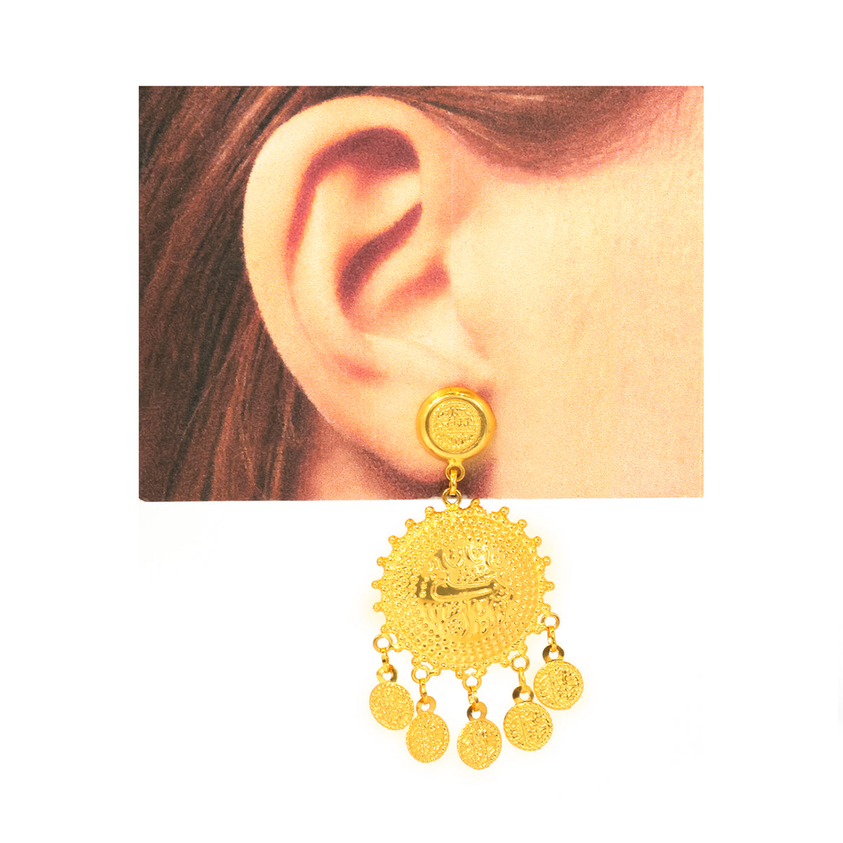 Gold earring worn on an ear with a plain background