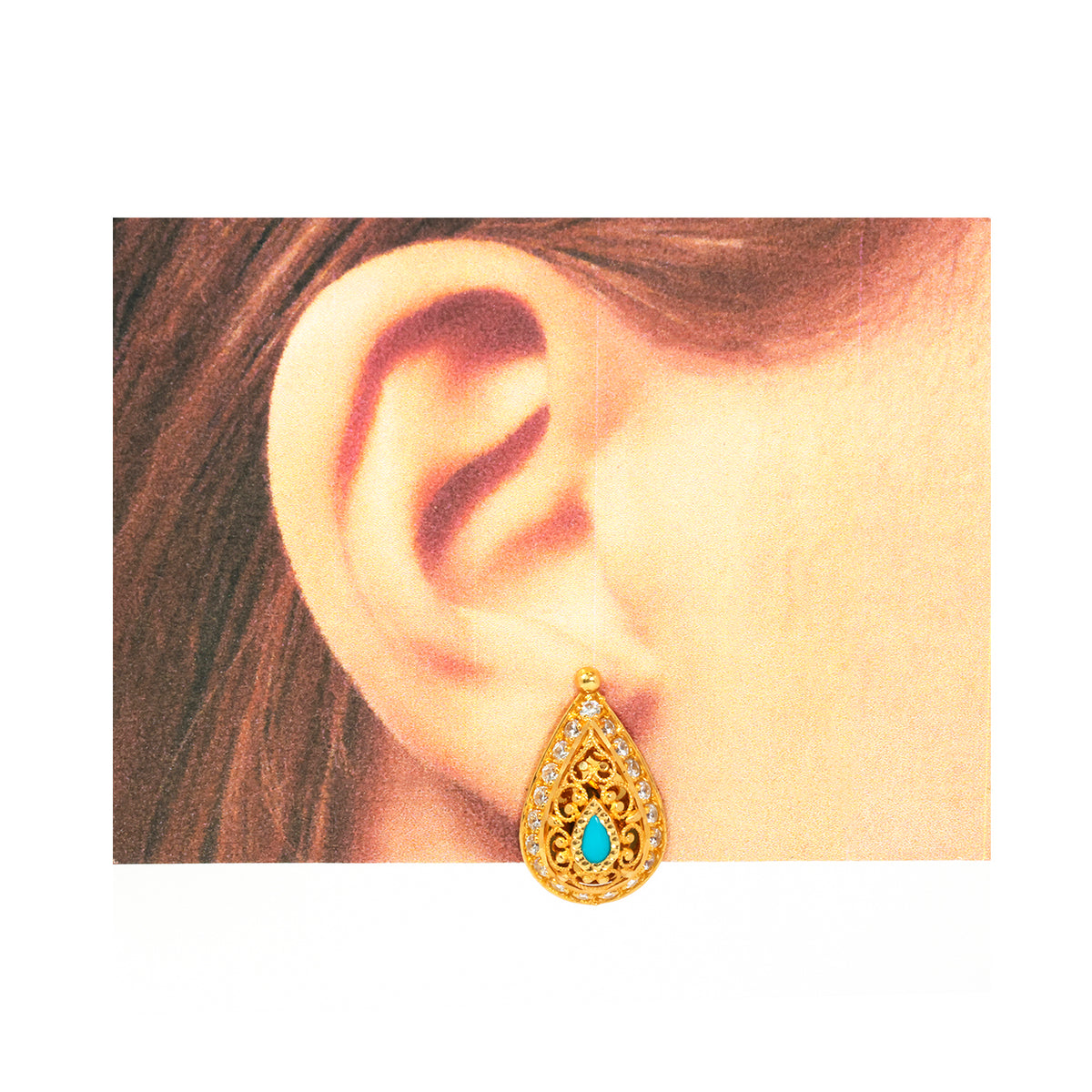 Gold earring with turquoise stone worn by a person
