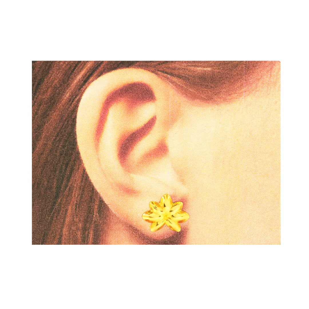 Close-up of an ear wearing a gold star-shaped earring on a white background
