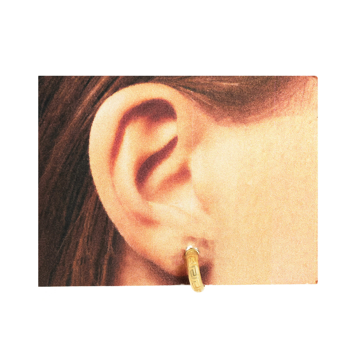 Gold hoop earring worn by a person with dark hair.