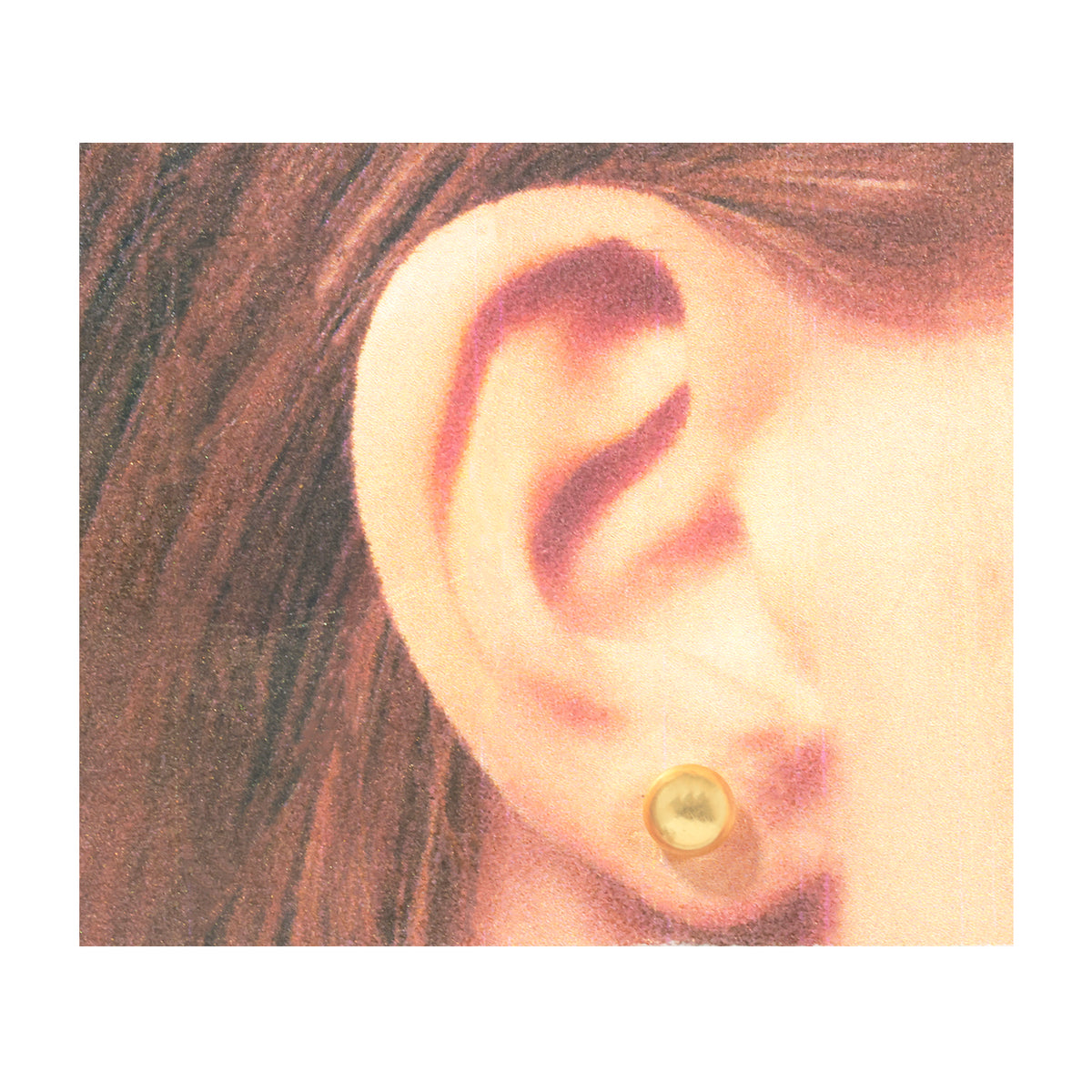 A close-up of a person's ear wearing a small yellow and white striped stud earring with a black dot.