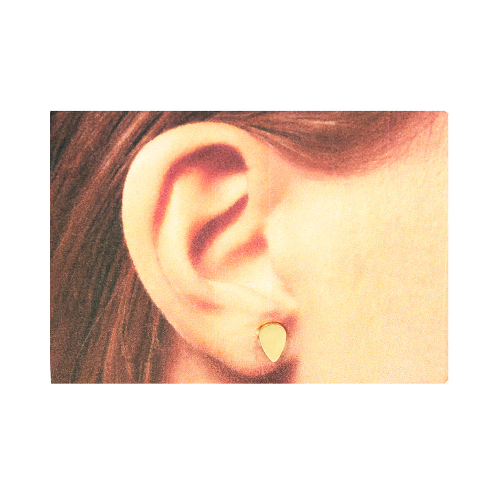 Close-up of an ear wearing a gold earring with a plain background