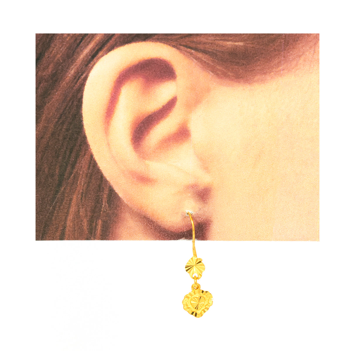 Gold earring worn on an ear with a plain background