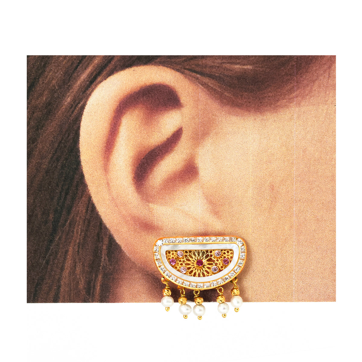 Gold earring with pearls worn by a person