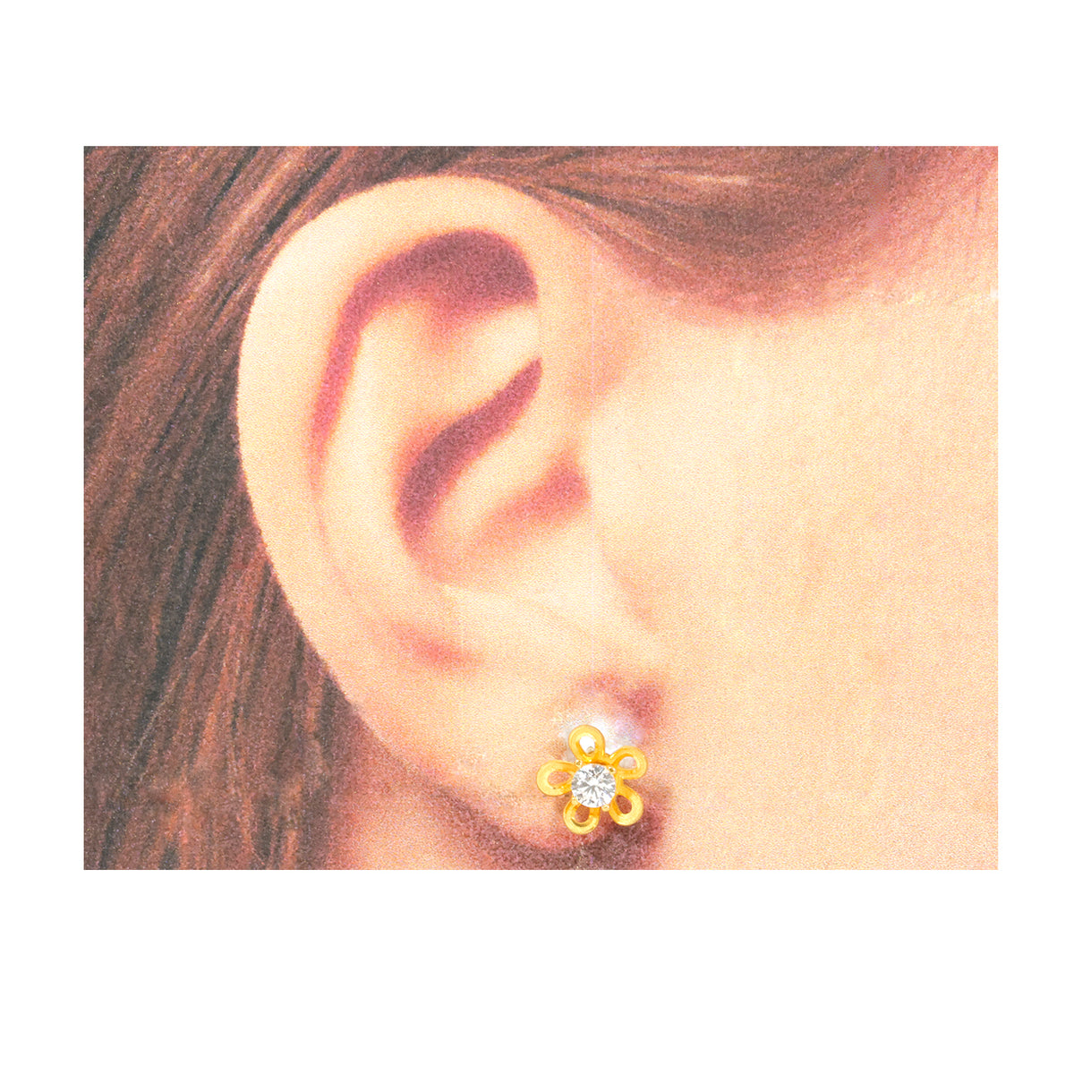 Gold flower-shaped earring worn on an ear with a plain background