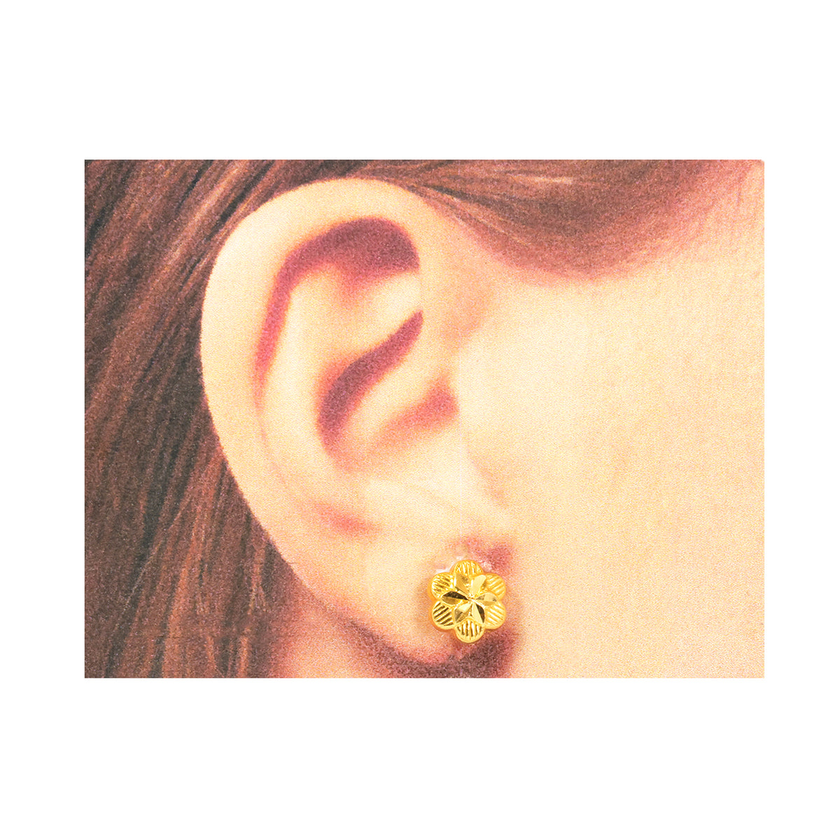 Gold floral earring worn on a person's ear with a neutral background