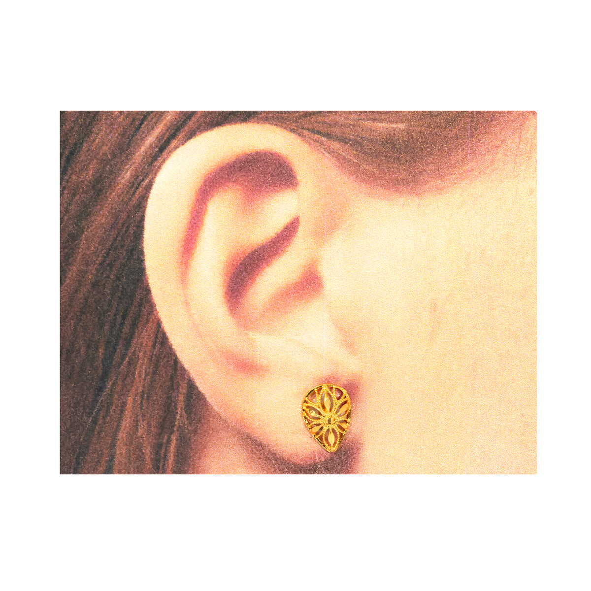 Gold earring worn on an ear with a plain background