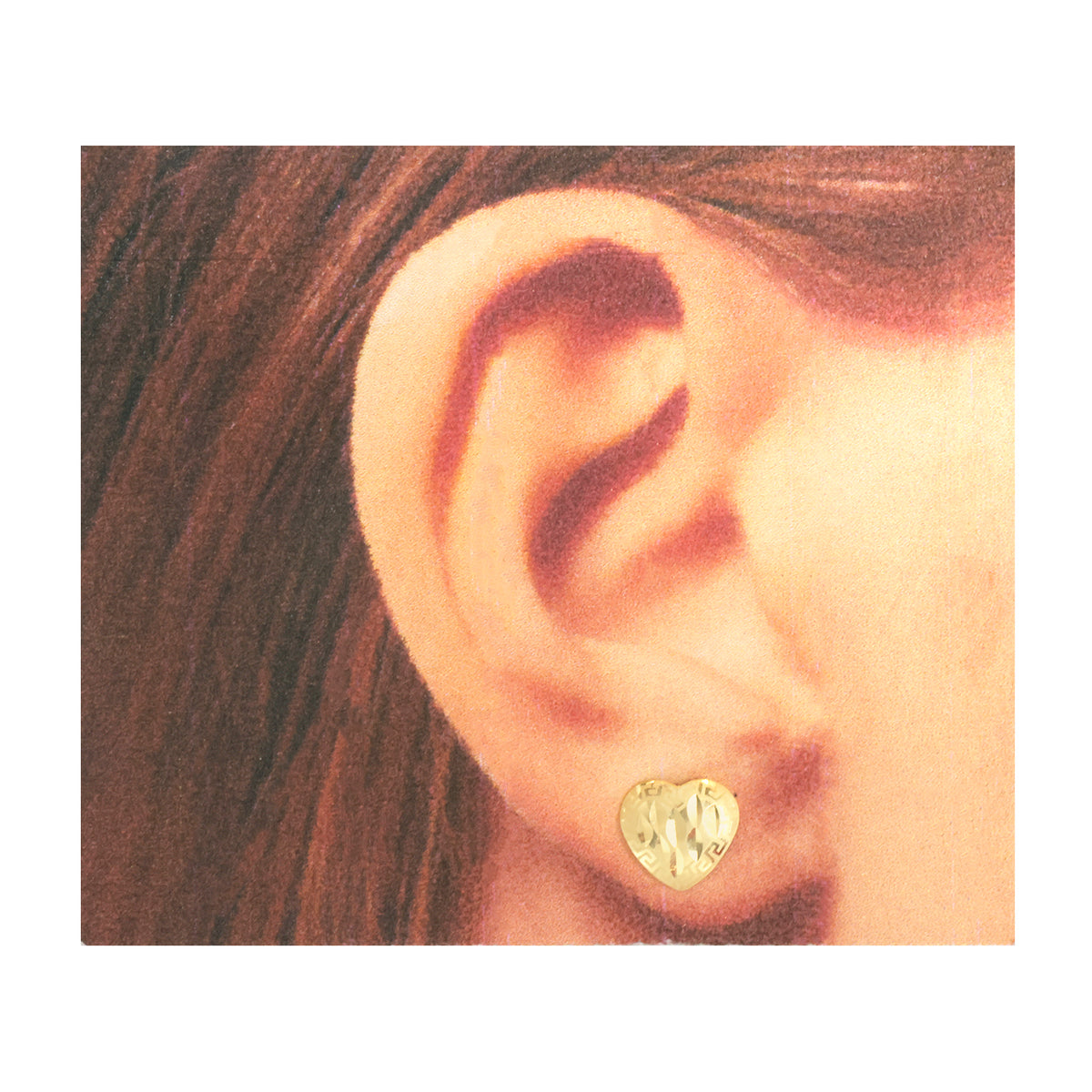 A close-up of a person's ear wearing a small textured gold heart-shaped stud earring, with brown hair visible on the left side.