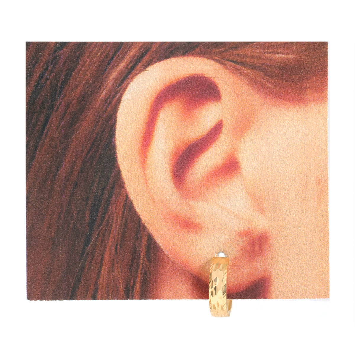 A close-up of a person's ear wearing a small textured gold hoop earring, shown against a plain white background.