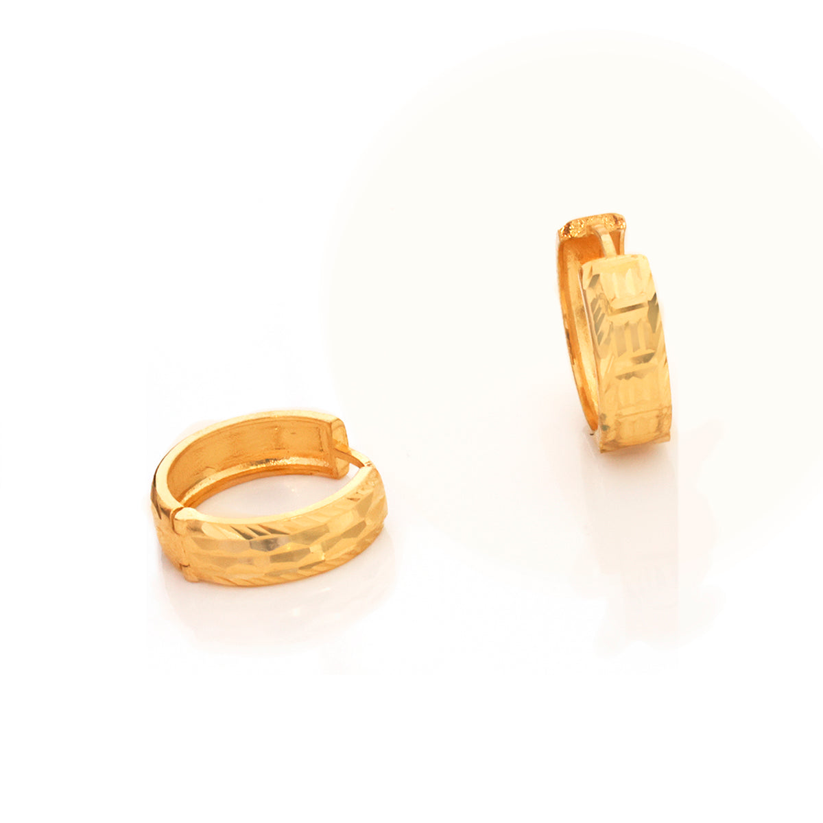 A pair of textured gold huggie hoop earrings shown on a clean white background, with one earring standing upright and the other lying on its side.