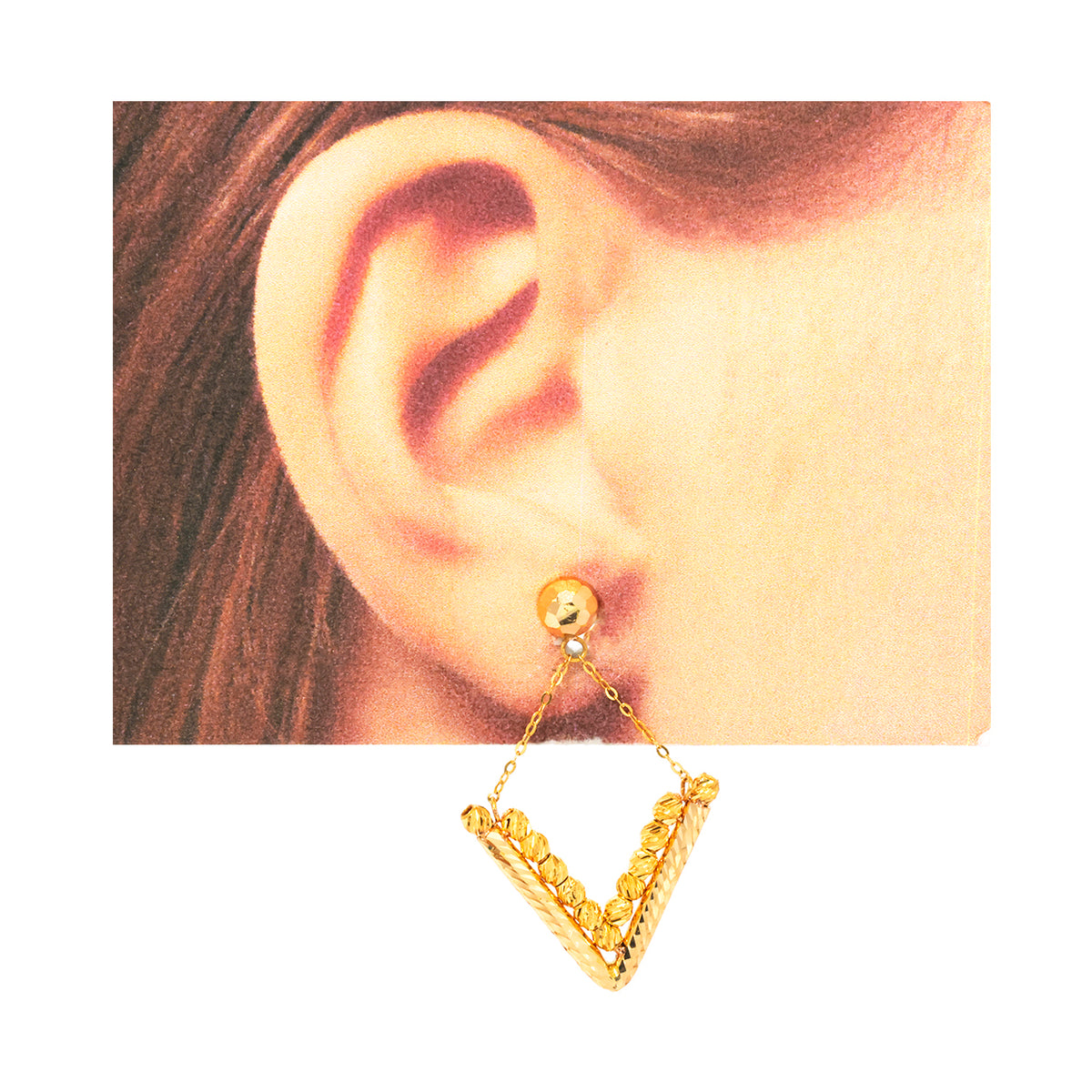 Gold earring worn on an ear with a plain background