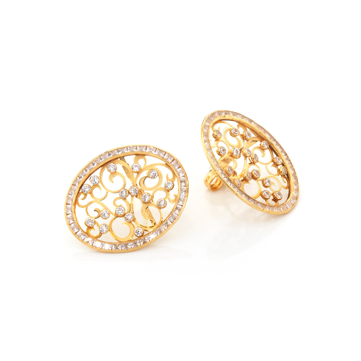 A pair of oval gold-tone earrings with intricate openwork scroll filigree and a border of small clear stones, shown on a clean white background.