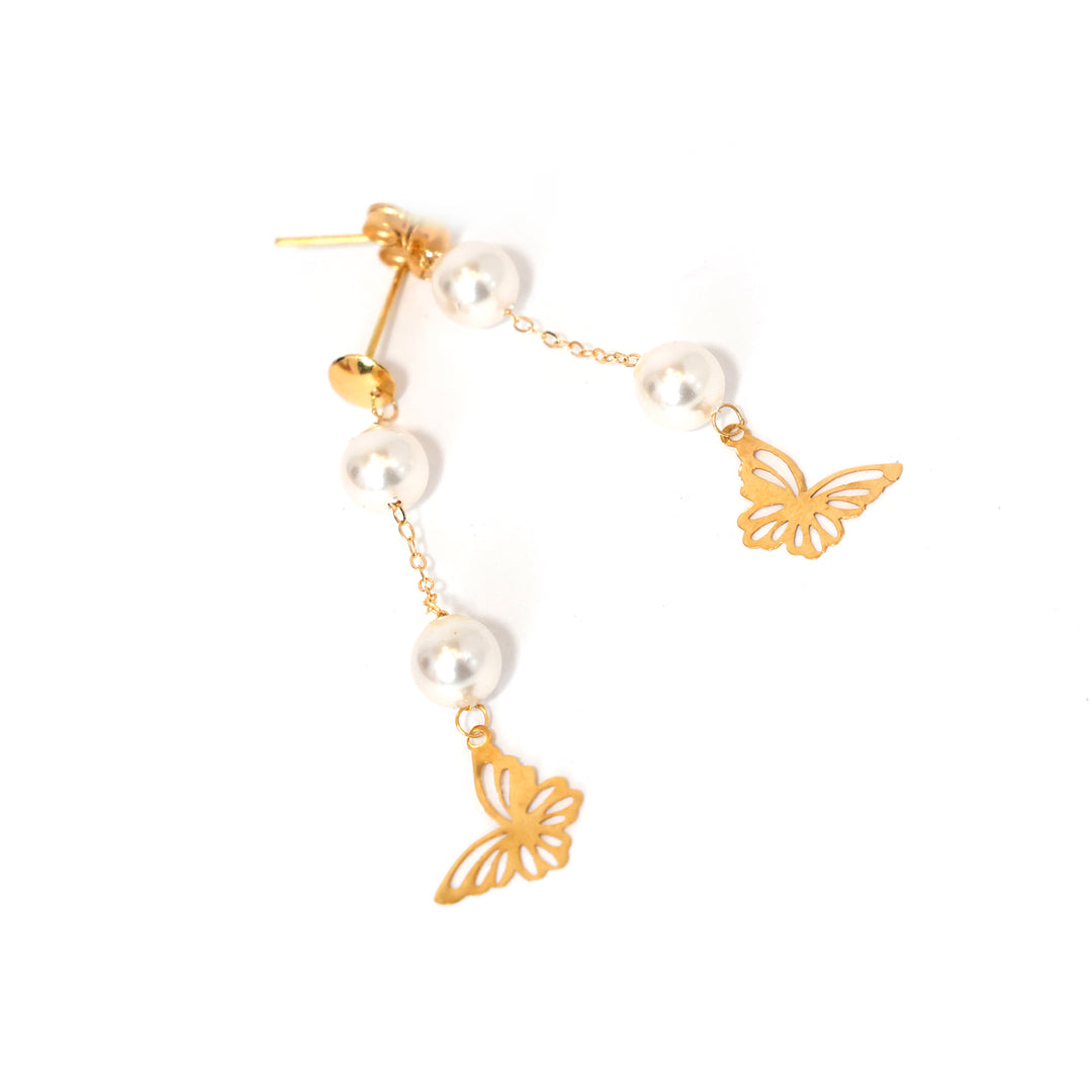 Gold butterfly and pearl earrings on a white background