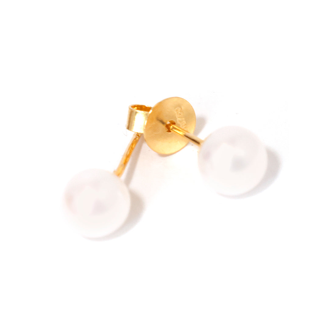 Gold earring with a white stone on a white background
