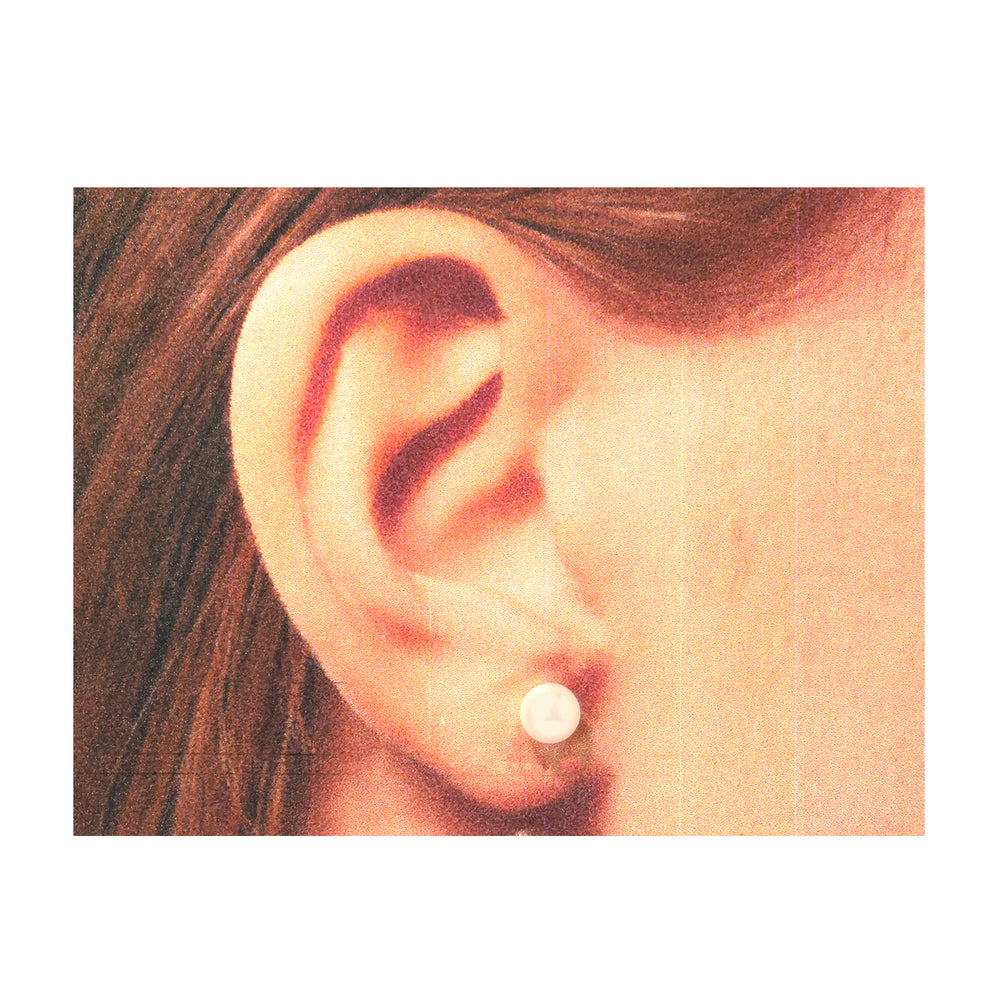 Close-up of an ear wearing a pearl earring with a plain background