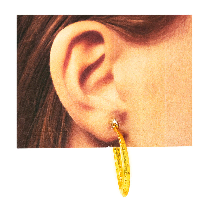 Gold hoop earring worn by a person with brown hair.