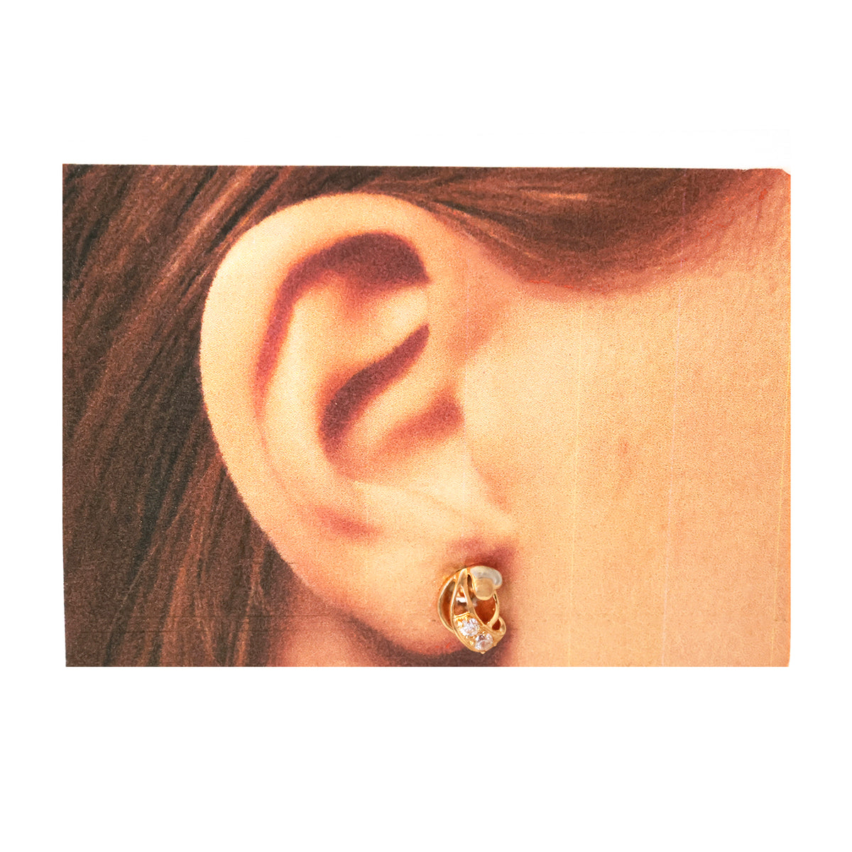 Close-up of an ear wearing a gold earring with a pearl center on a white background