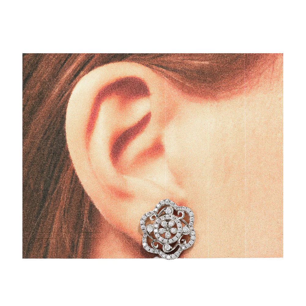 Close-up of an ear wearing a decorative silver earring with a white background
