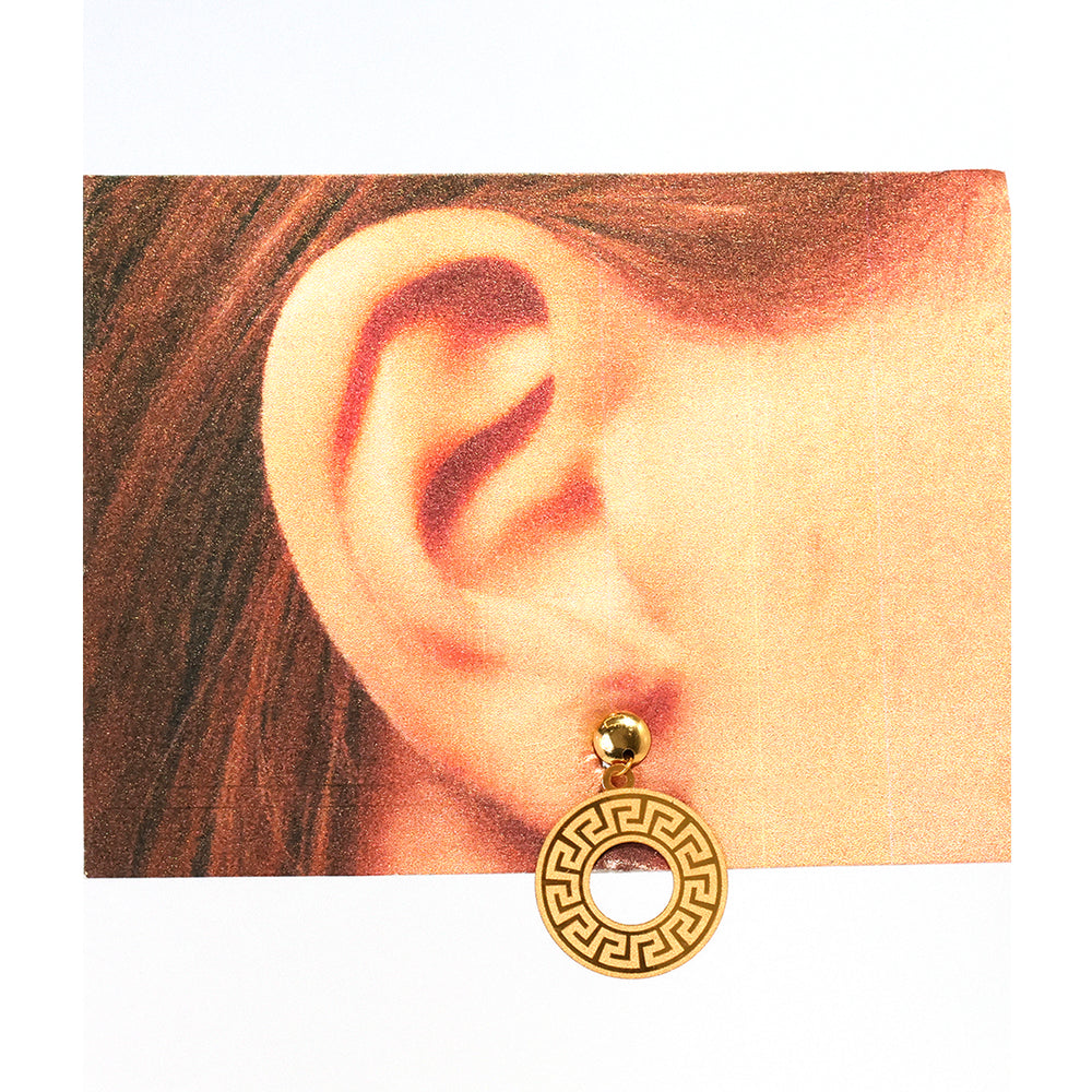 Gold earring worn on an ear with a plain background