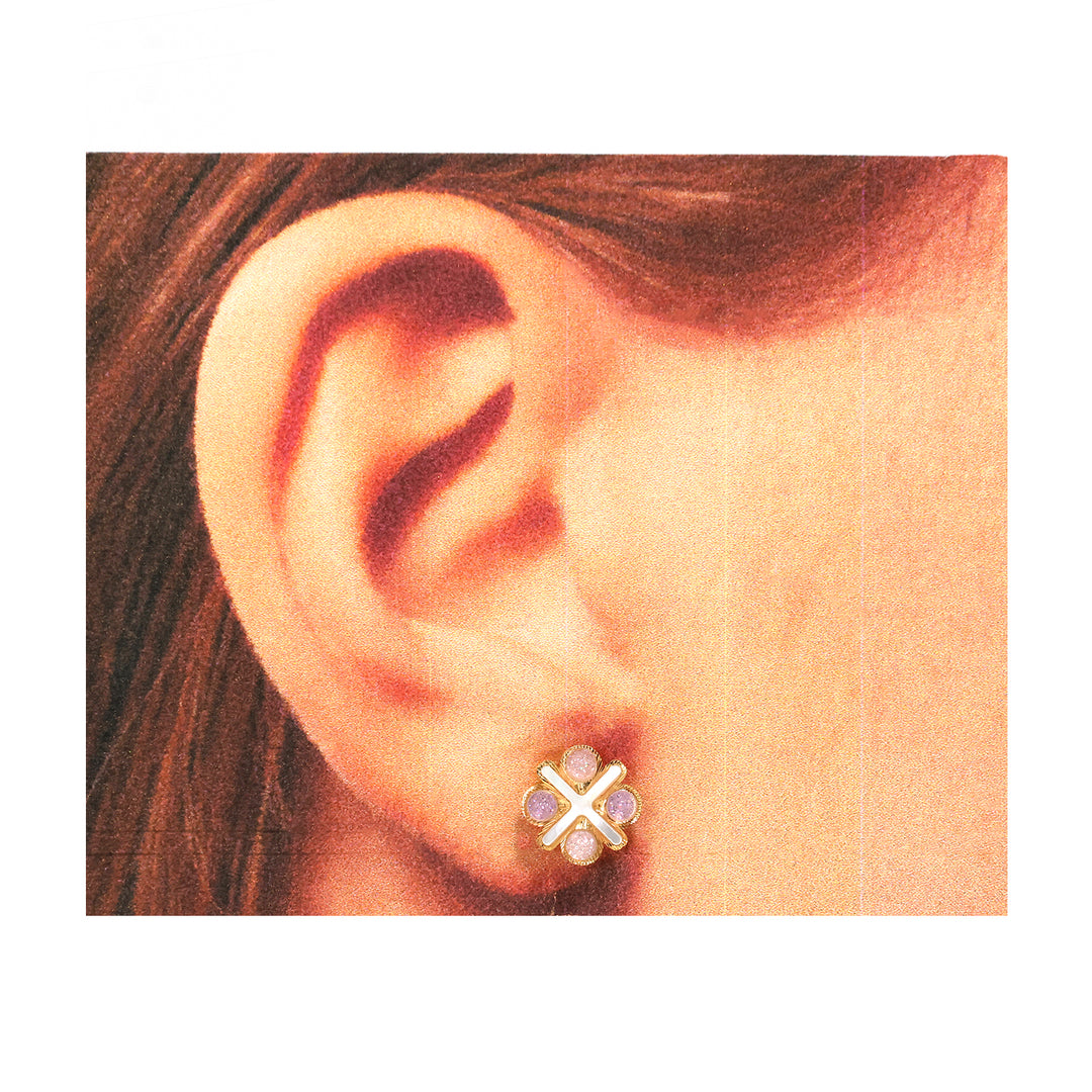 Close-up of an ear wearing a floral earring with gold and purple details.