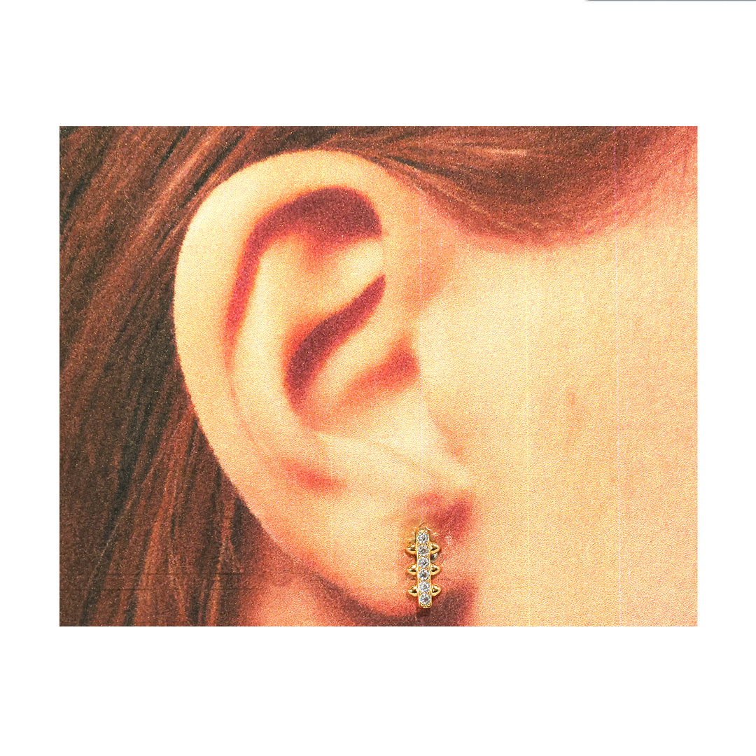 Close-up of an ear wearing a diamond earring with a white background