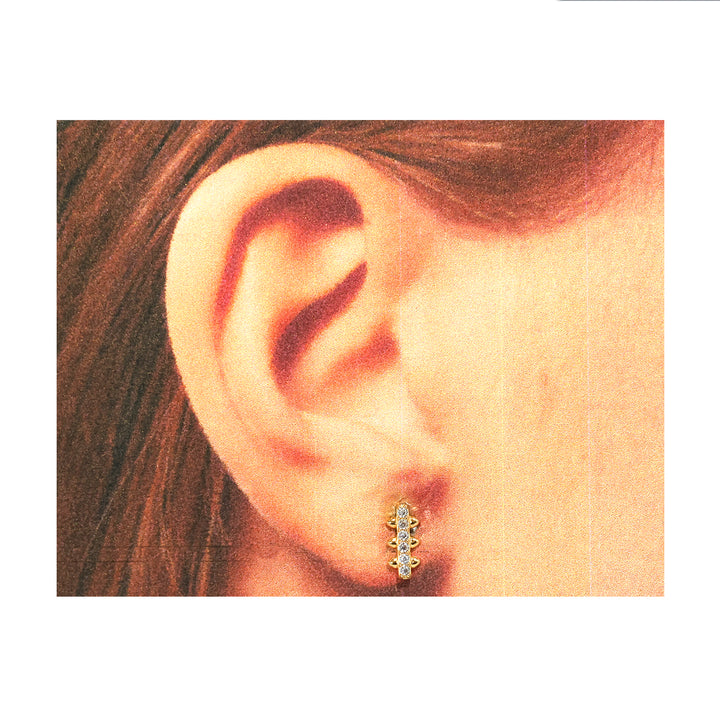 Close-up of an ear wearing a diamond earring with a white background