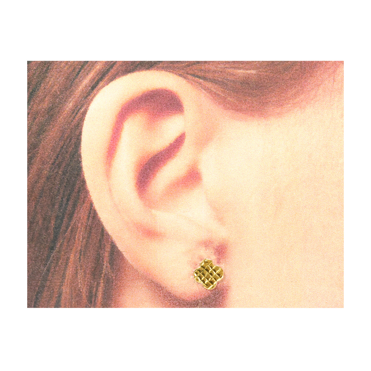 A close-up of a person's ear wearing a small gold stud earring with a textured geometric pattern.