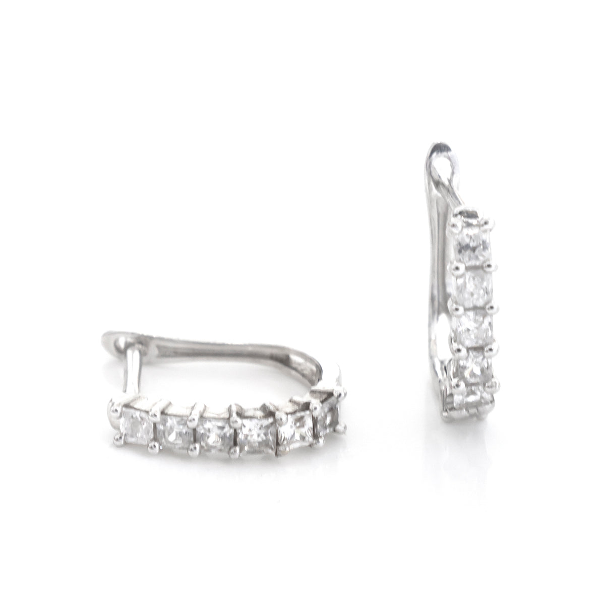 A pair of silver-toned huggie hoop earrings with a row of clear rectangular gemstones, shown from the side on a white background.