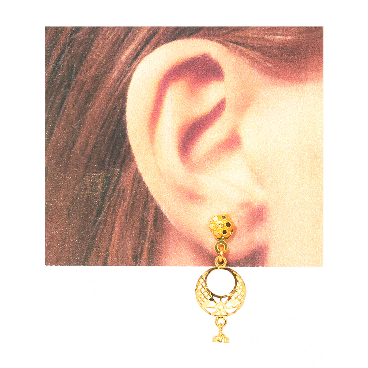 A gold-toned dangle earring with a textured spherical top and a crescent moon-shaped lower charm, shown worn on a person's ear against a white background.