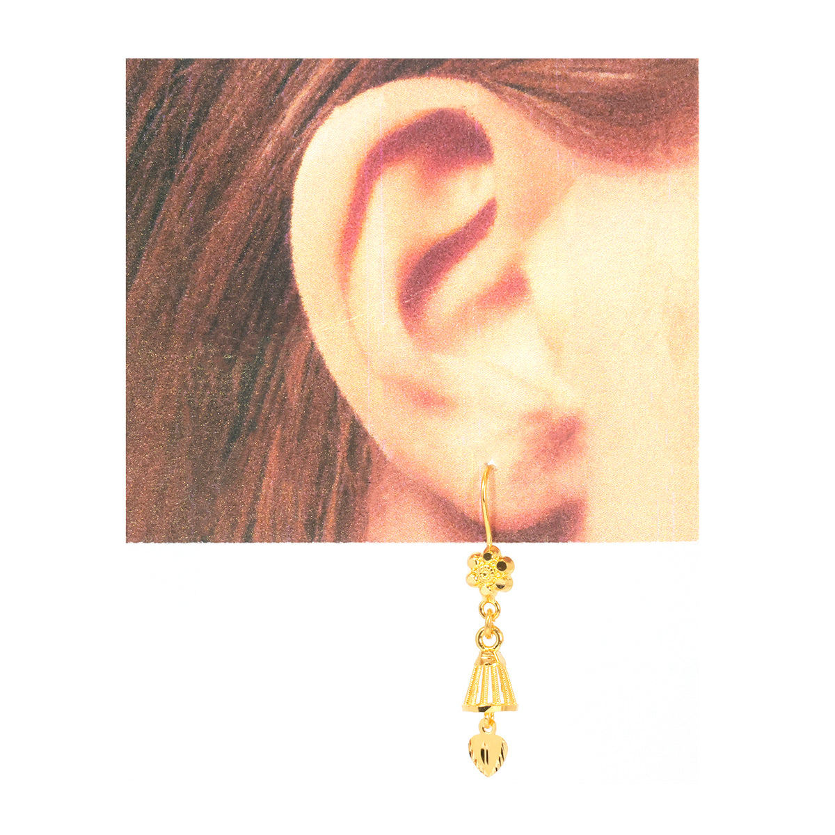A gold dangle earring with a small floral cluster and three dangling geometric charms, shown worn on a person's ear against a white background.