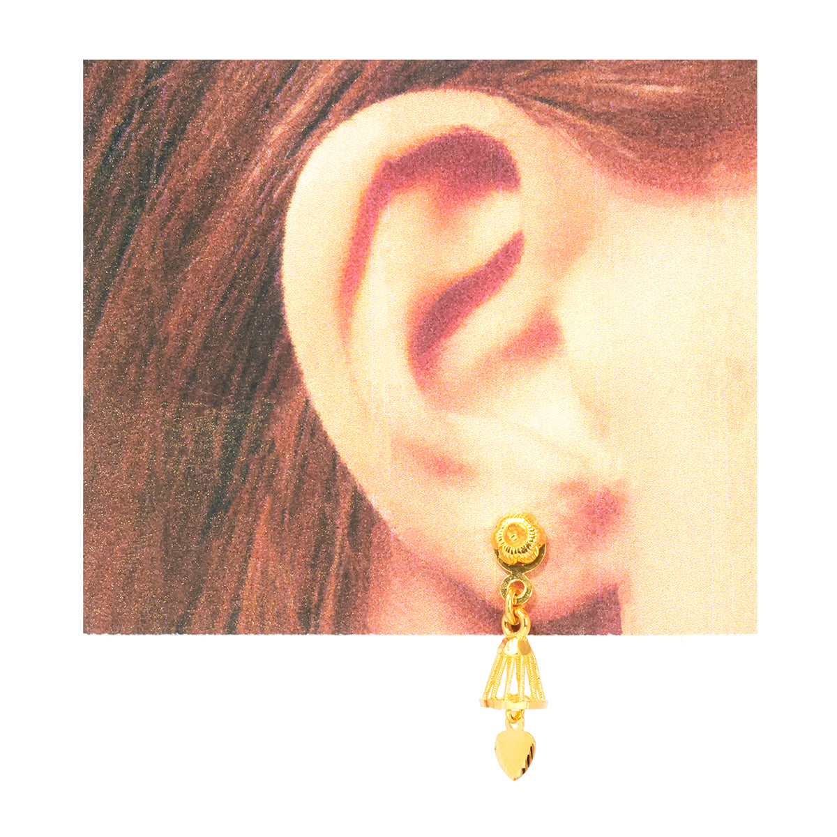 A gold dangle earring with a textured circular top, a triangular link, and a small heart-shaped drop, shown worn on a person's ear against a white background.