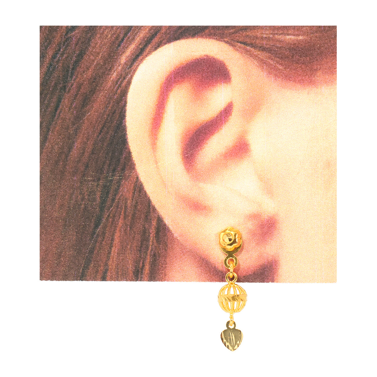 A gold dangle earring with a rose-shaped stud, a faceted bead, and a small dangling charm, shown worn on a person's ear against a white background.