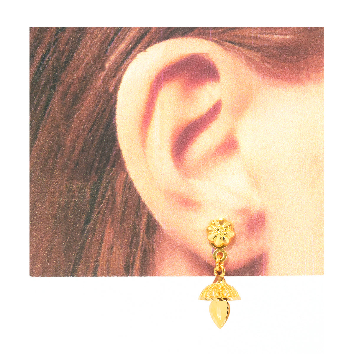 A gold-toned double-drop dangle earring worn on a person's ear, shown against a white background with a printed close-up of the ear behind it.