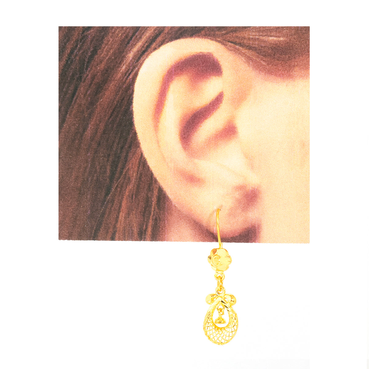 A gold dangle earring with a decorative filigree pendant, shown hanging below a cropped photo of an ear wearing it, on a plain white background.