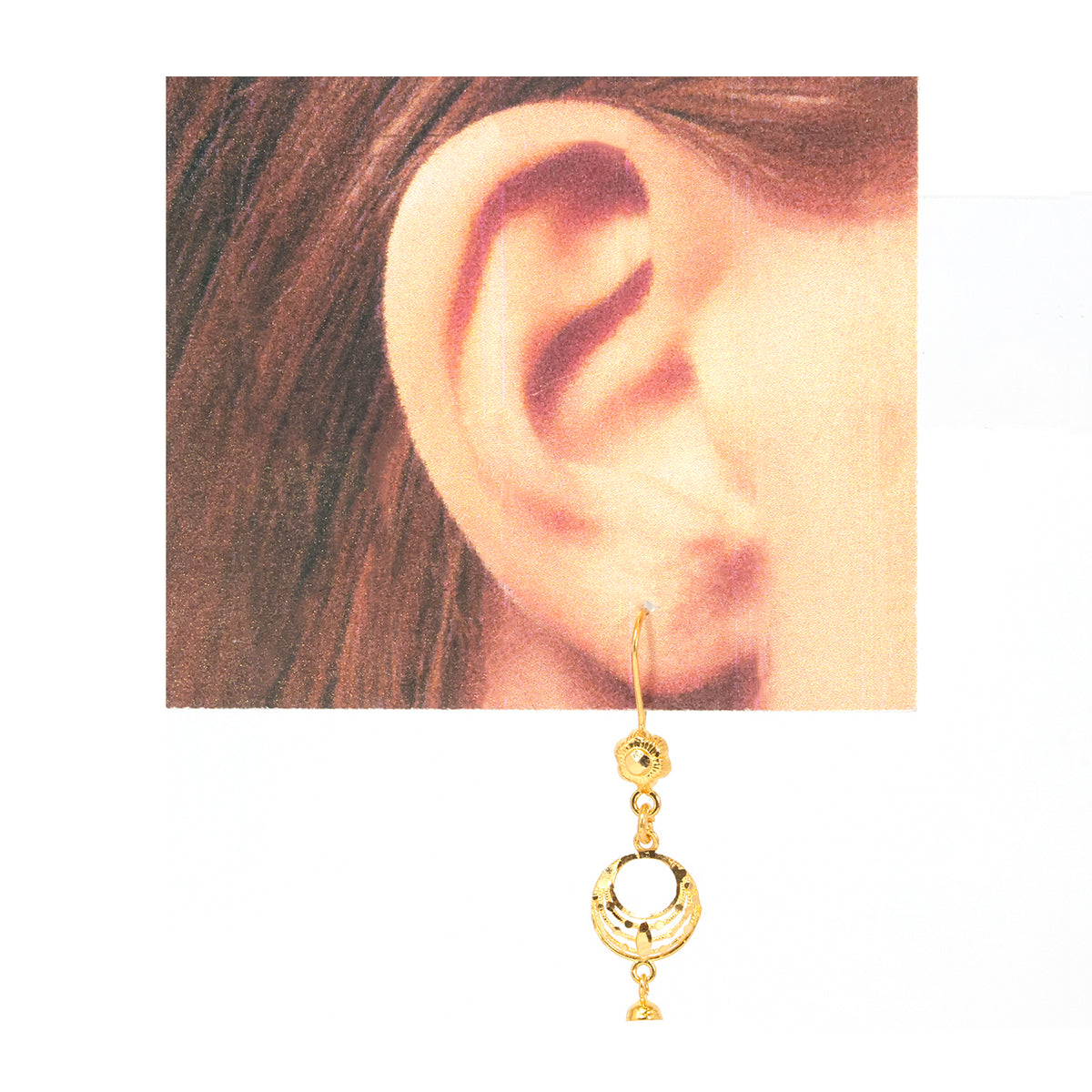 A gold dangle earring with a small floral cluster and three dangling geometric charms, shown worn on a person's ear against a white background.