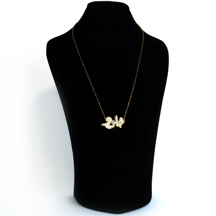 Gold necklace on a black mannequin bust against a white background