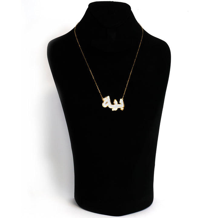 Gold necklace with a pendant on a black mannequin bust.