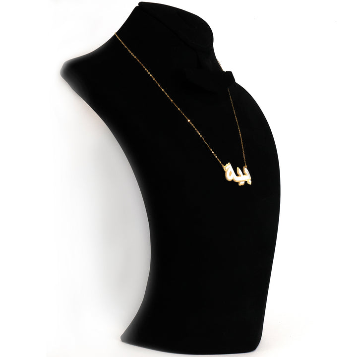 Gold necklace on a black mannequin bust against a white background