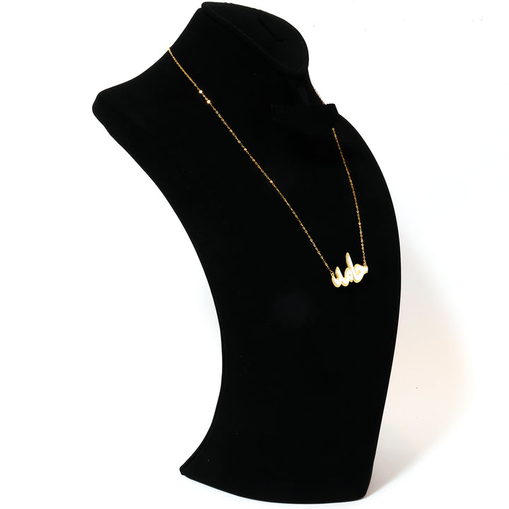 Gold necklace on a black mannequin bust against a white background