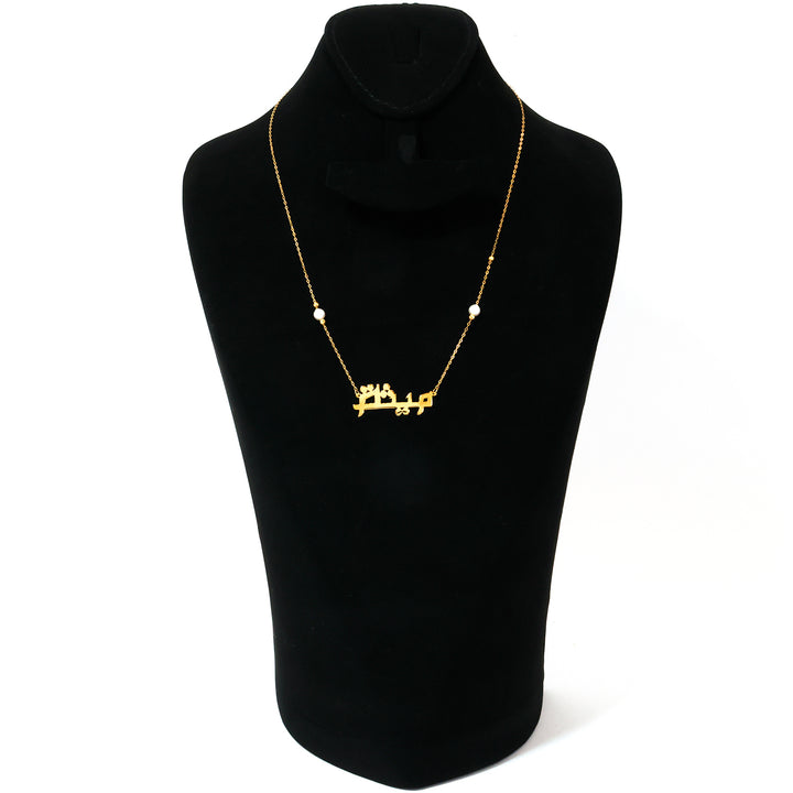 Gold necklace with Arabic script on a black mannequin bust against a white background