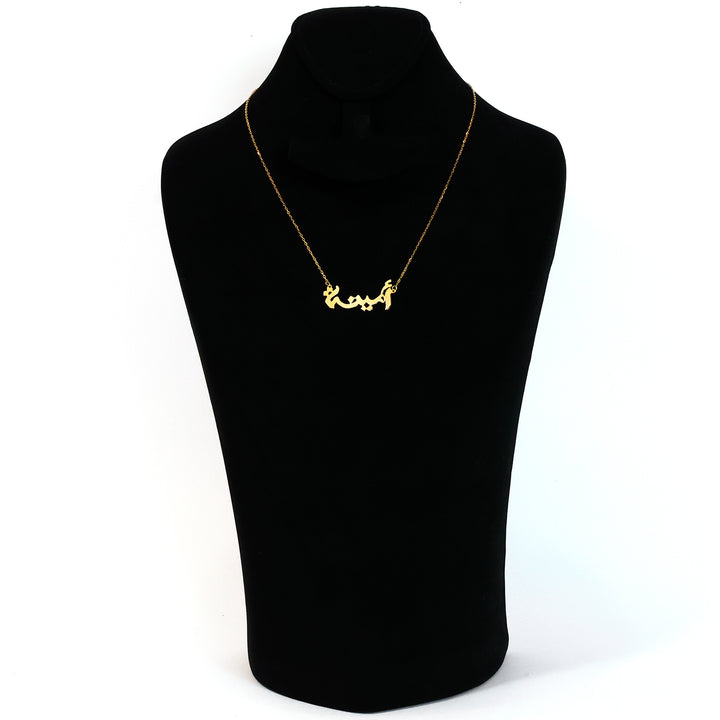 Gold necklace on a black mannequin bust against a white background