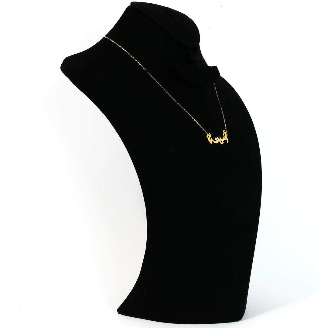 Gold necklace on a black mannequin bust against a white background