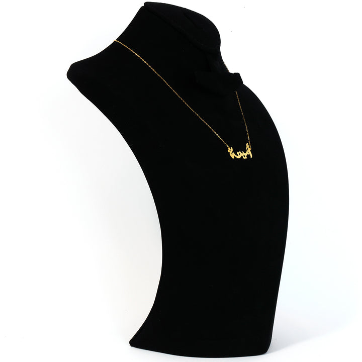 Gold necklace on a black mannequin bust against a white background