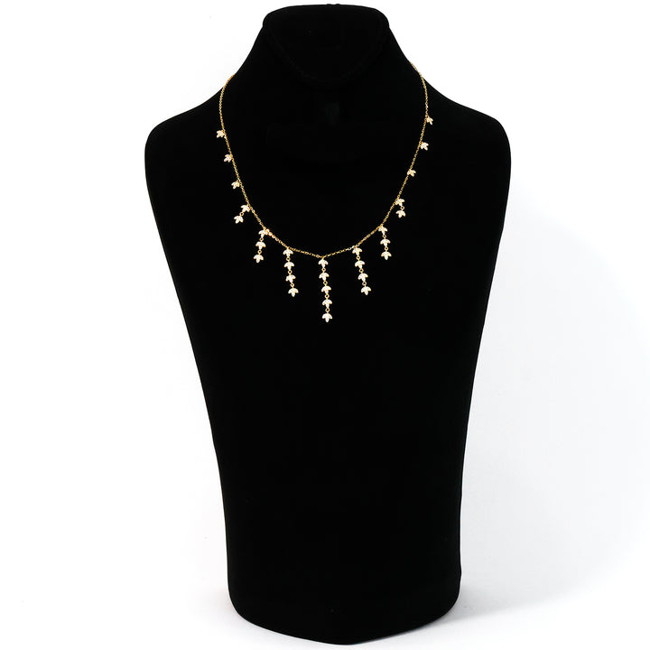 Gold necklace on a black mannequin bust against a white background